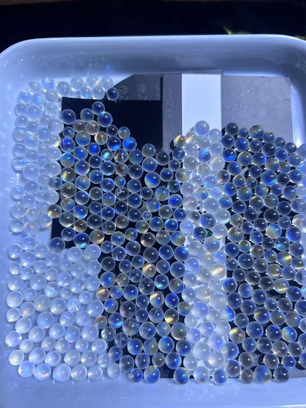 Rainbow moonstone beads from a production lot, showing blue flash under workshop light